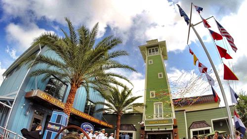 The Boathouse at Disney Springs dazzles with its green tower, waving flags, and palm trees greeting guests at the entrance.