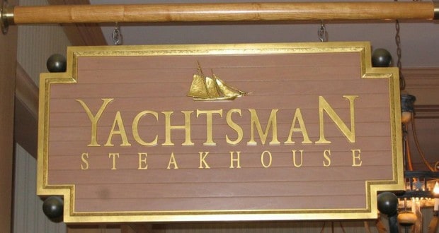 The Yachtsman Steakhouse sign, with gold lettering and a sailboat, greets guests at Disney’s Yacht Club Resort’s steakhouse.