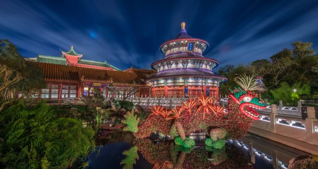 Epcot’s Chinese-style temple and glowing dragon sculpture shimmer in the pond, an iconic nighttime Disney World photo spot.