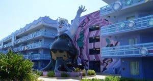 Ursula statue greets guests outside a vibrant, ocean-themed Disney World Resort hotel with blue balconies and sea-inspired decor.