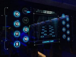 Blue digital board with numbered circles and room assignments, evoking the thrilling vibe of Disney World attraction entrances.