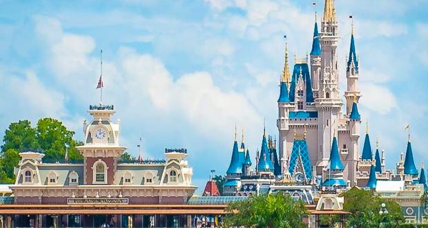Cinderella Castle and Main Street entrance with clock tower, set against blue skies and clouds—Disney magic awaits your adventure.