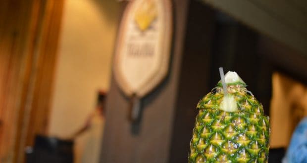 A festive pineapple drink with a straw and garnish, ready to enjoy at Disney World's immersive resort dining experiences.