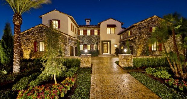 Illuminated stone mansion with palm trees and a manicured path at night, evoking Disney resort luxury and dream vacation vibes.