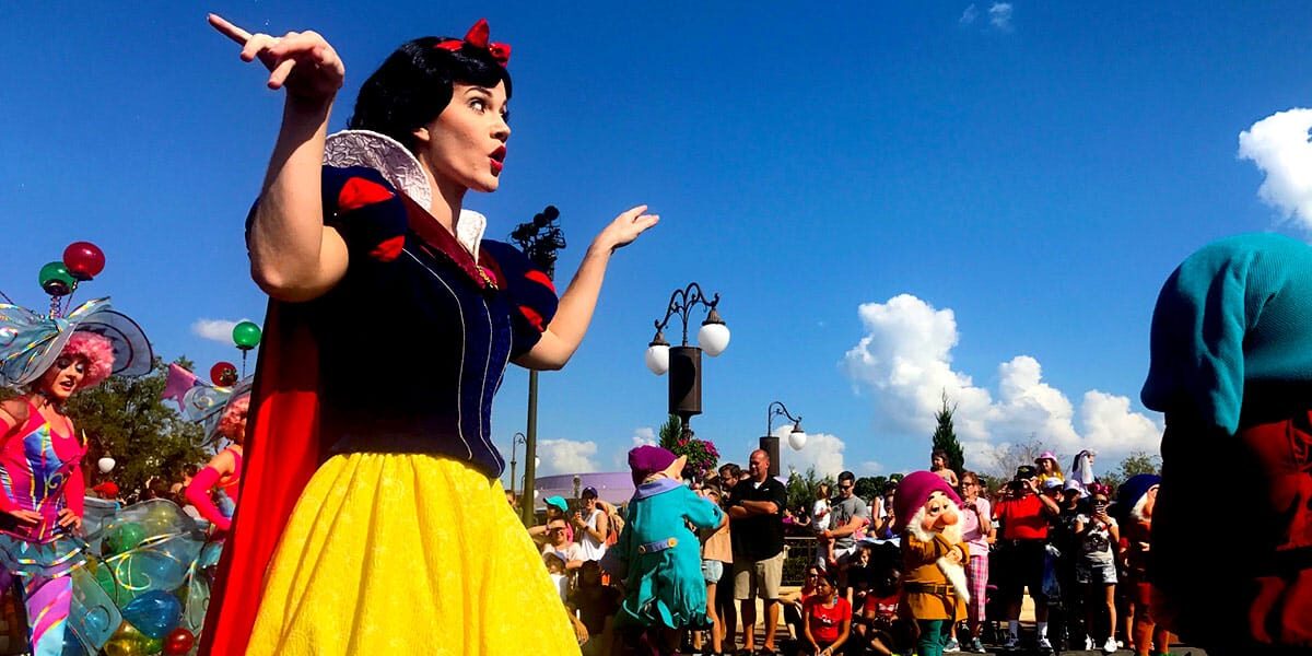 Snow White delights guests in a vibrant parade, waving amid beloved characters and fans during a magical Disney celebration.