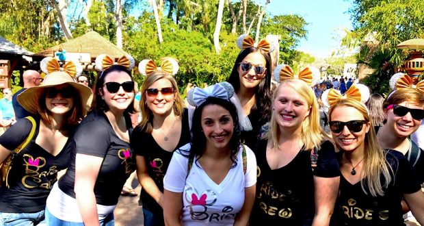Bachelorette squad in matching shirts and Minnie ears at Cinderella Castle, bride in silver ears, captured by Memory Maker.