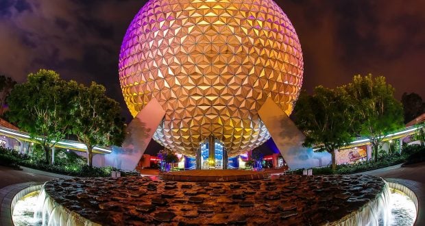 Spaceship Earth at Epcot shines in vibrant night lights, with dancing fountains ahead, creating pure Disney World magic.