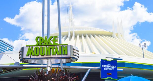 Space Mountain entrance sign at Magic Kingdom, backed by its sleek white building and blue sky—an iconic Disney World adventure.