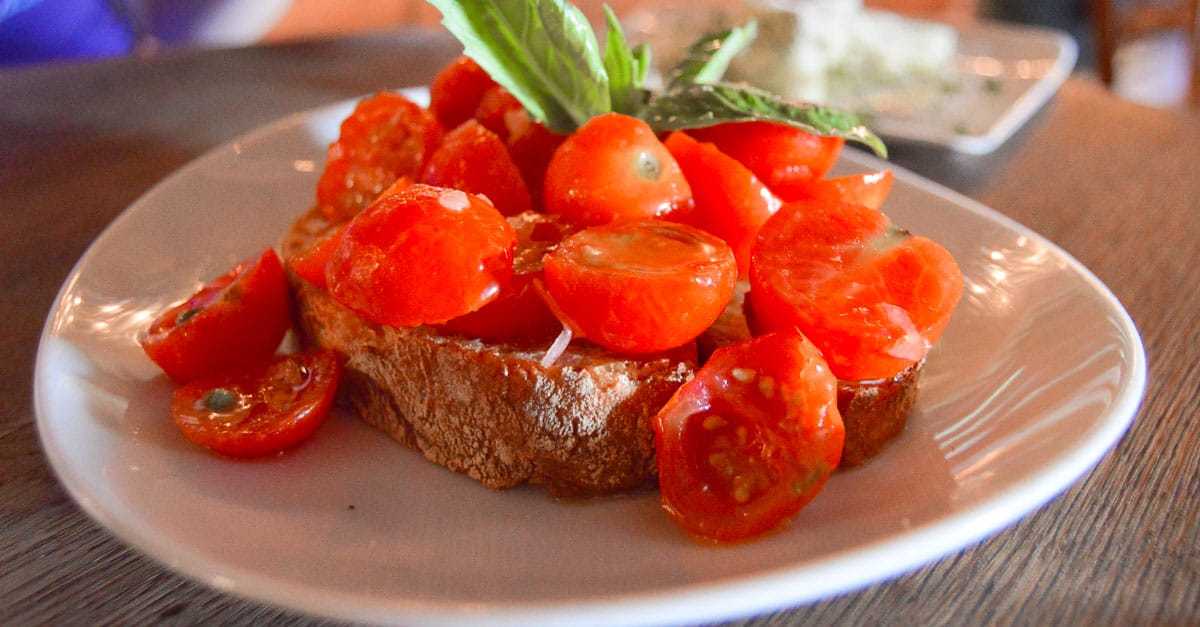 Crispy bread with cherry tomatoes and basil, just like the flavorful bites served at Disney Deluxe Resorts’ signature dining spots.