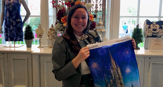 Guest in a gray blazer shops for Disney souvenirs, beaming with a castle-and-fireworks bag, ready to unlock Pro Tips magic.