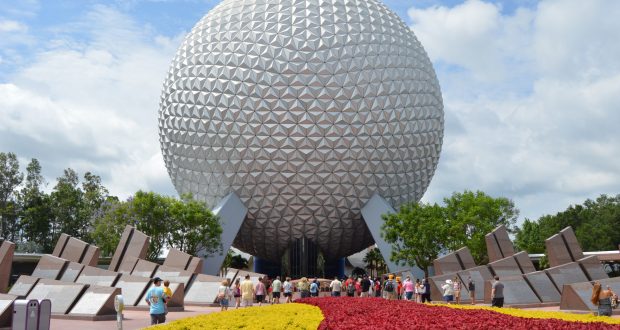 Guests flock toward Epcot’s iconic geodesic sphere, framed by vibrant gardens—an unforgettable Disney park experience.