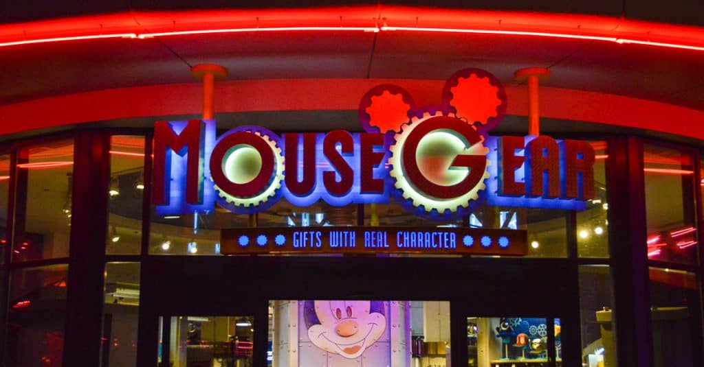 Mouse Gear sign glowing with Mickey ears and neon, entrance below—Disney World’s go-to spot for exclusive merch and shopping secrets.