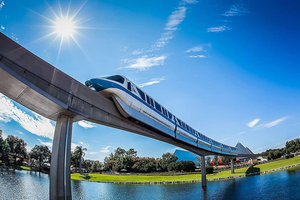 The Disney World Monorail glides above shimmering water under sunny skies, kicking off a legendary Monorail Bar Crawl.