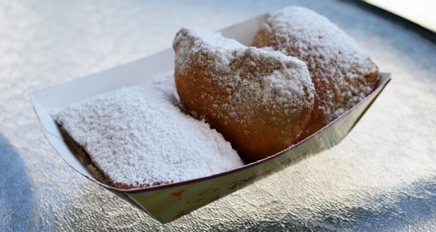 Three classic beignets dusted with powdered sugar, served in a paper tray—an iconic Disney resort snack found at moderate resorts.