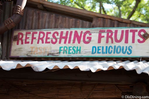 REFRESHING FRUITS Tasty Fresh Delicious" sign above a metal roof in Animal Kingdom—check nearby for snacks and photo ops!.