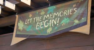 LET THE MEMORIES BEGIN!" banner at Disney's Animal Kingdom with vibrant leaves and starbursts, welcoming guests to adventure.