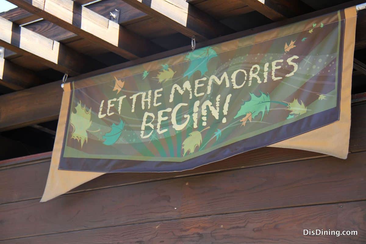 LET THE MEMORIES BEGIN!" banner at Disney's Animal Kingdom with vibrant leaves and starbursts, welcoming guests to adventure.