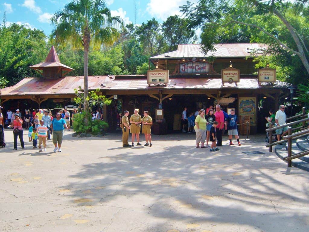 Guests gather outside Disneyland’s iconic Jungle Cruise, FastPass signs visible amid lush trees and bright sunlight.