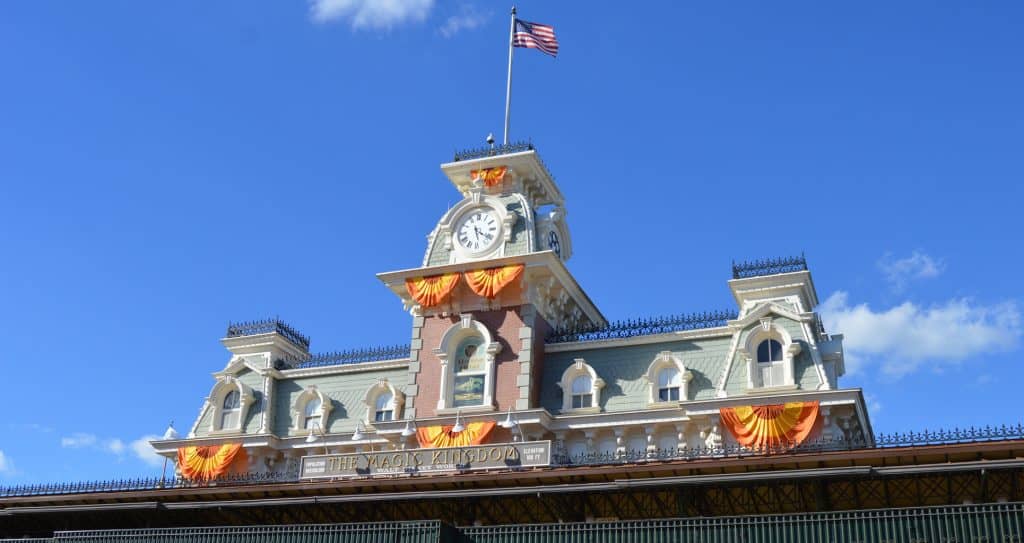 Magic Kingdom’s entrance pops with orange and yellow banners, the American flag flying high—your magical adventure starts immediately!.