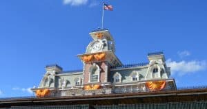 Magic Kingdom’s entrance pops with orange and yellow banners, the American flag flying high—your magical adventure starts immediately!.