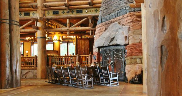 A resort lobby with rocking chairs and a grand stone fireplace, evoking the immersive charm of classic Disney World lodges.