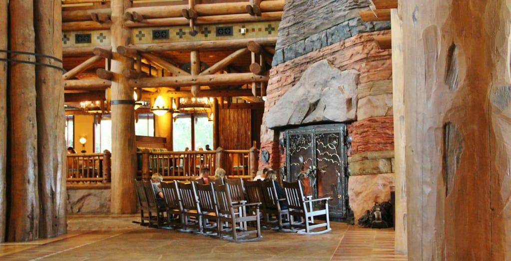 A resort lobby with rocking chairs and a grand stone fireplace, evoking the immersive charm of classic Disney World lodges.