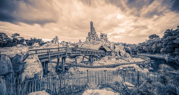 Sepia photo of Big Thunder Mountain Railroad at Walt Disney World, showcasing its iconic rugged peaks and wooden trestle bridge.