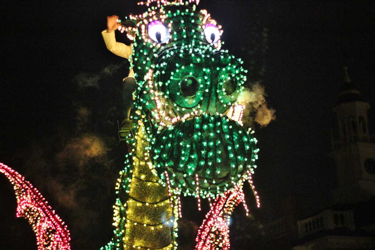 Maleficent dragon float glowing with colorful lights and smoky breath dazzles crowds during Disney World's nighttime parade.