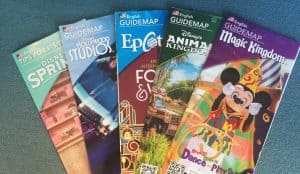 Disney World guidemaps fanned out on blue, showcasing vibrant covers—your ticket to every magical secret in the parks.
