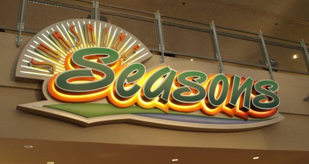 Sunshine Seasons" sign with vibrant sunburst greets guests at EPCOT, inviting you into this colorful Disney dining spot.