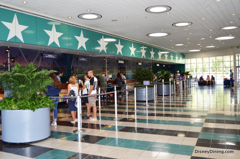 Disney fans line up in a lively, star-adorned lobby at a Value Resort, sunlight streaming through big windows for an energetic welcome.