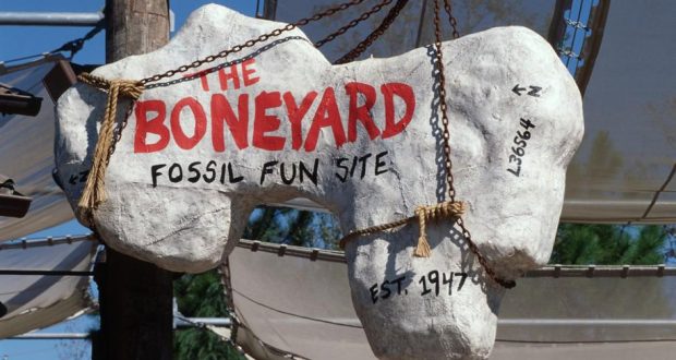 The Boneyard’s giant bone-shaped entrance sign, marked “Est. 1947,” swings above the DinoLand U.S.A. fossil dig site.