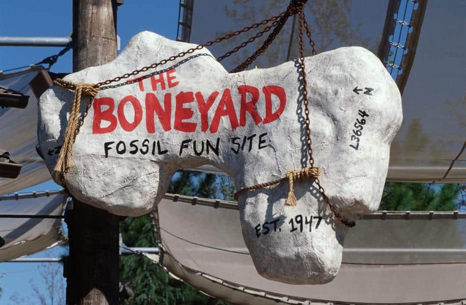 The Boneyard’s giant bone-shaped entrance sign, marked “Est. 1947,” swings above the DinoLand U.S.A. fossil dig site.