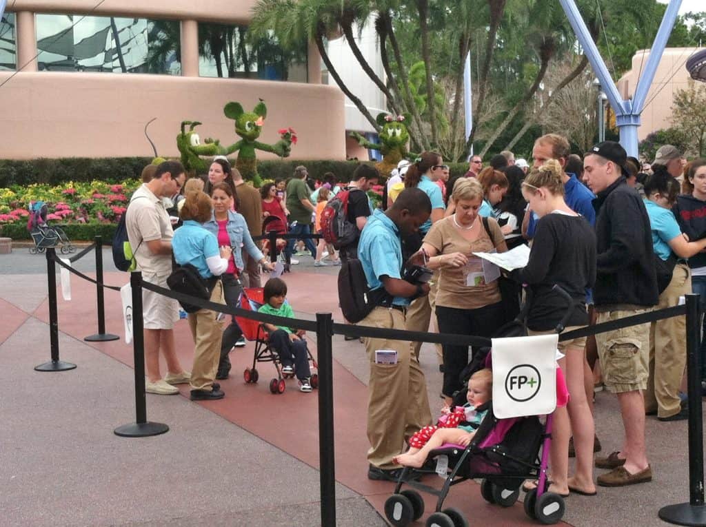 Guests form a queue at Disney World as helpful Cast Members assist and families keep kids in strollers, ensuring a magical visit.