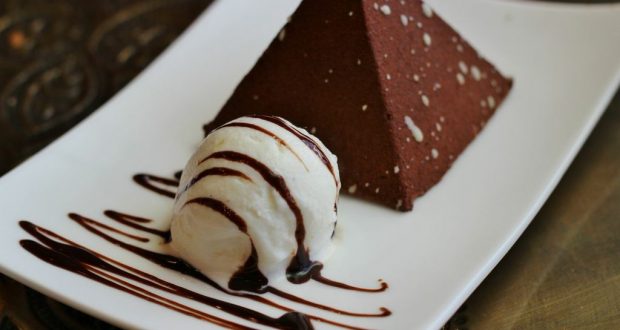 Chocolate pyramid dessert at Disney World, topped with rich sauce and vanilla ice cream, served on a sleek white plate.