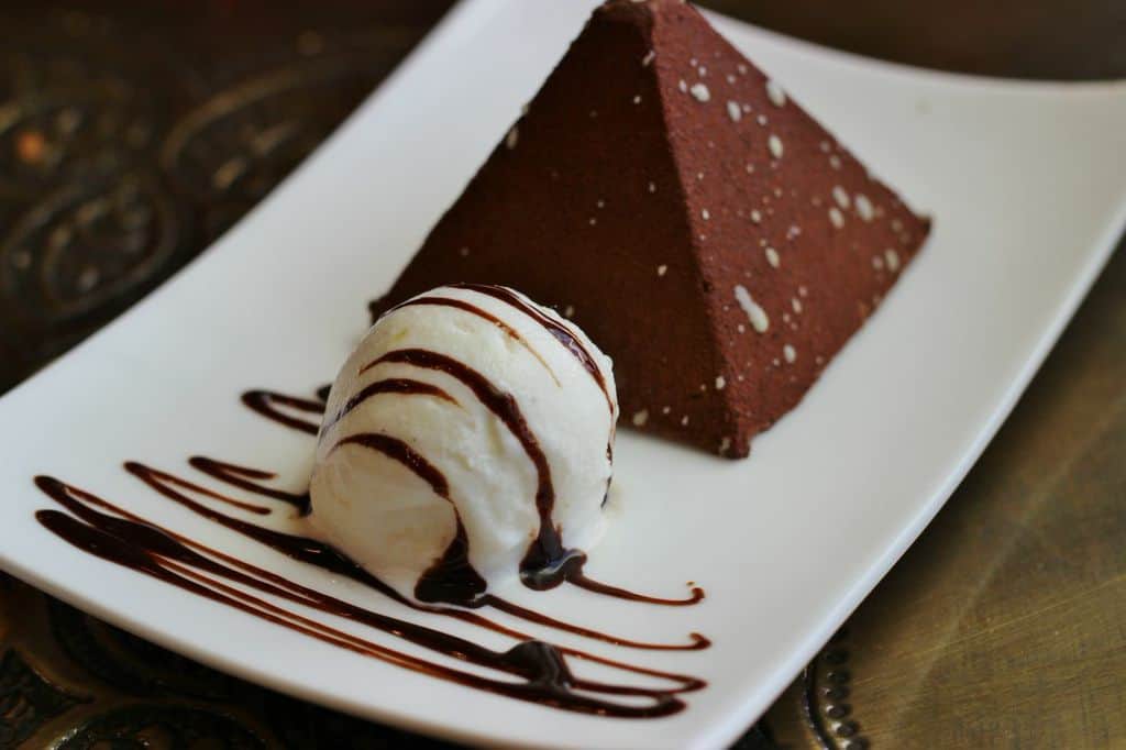 Chocolate pyramid dessert at Disney World, topped with rich sauce and vanilla ice cream, served on a sleek white plate.