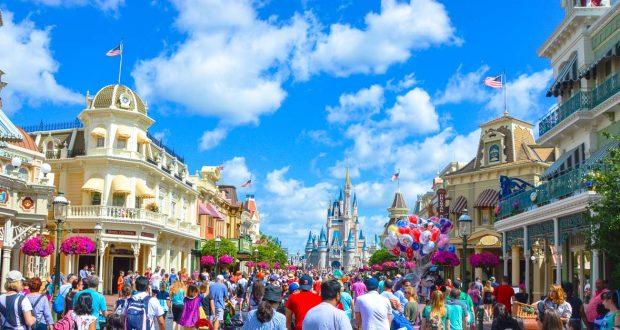 Guests fill Main Street, moving toward Cinderella Castle at Magic Kingdom under a vibrant blue sky, ready for a perfect Disney day.