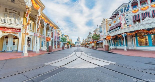 Main Street USA at Magic Kingdom shines with festive fall décor, leading to Cinderella Castle beneath a vibrant blue sky.