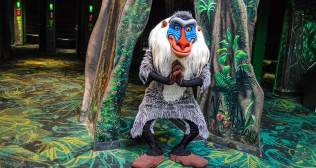 Rafiki from The Lion King greets guests in a lush, Animal Kingdom-inspired jungle setting celebrating hidden gems.