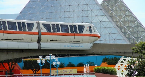 A sleek Disney monorail glides past the iconic glass pyramids and vibrant walls of EPCOT, capturing the magic of Walt Disney World.