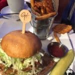 Classic Planet Hollywood burger with lettuce, waffle fries, pickle spear, and ketchup—theme park dining at Disney Springs.