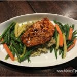 Savor glazed salmon on rice with green, yellow beans, and carrots—served at Planet Hollywood Observatory in Disney World.