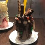 Over-the-top chocolate milkshake at Planet Hollywood, Disney World, topped with candy, brownie, wafer stick, and a yellow straw.
