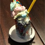 Planet Hollywood Observatory’s vibrant milkshake, loaded with cotton candy, lollipop, and yellow straw—a Disney Springs delight!.