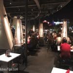 Nighttime Disney Springs patio with diners, glowing heaters, and city lights—ideal for unwinding after Planet Hollywood.