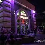 Planet Hollywood Observatory glows purple at night in Disney Springs, buzzing with guests exploring and relaxing around the entrance.