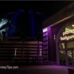 Planet Hollywood Observatory glowing purple at night in Disney Springs, with www.MickeyTips.com shown in the corner.