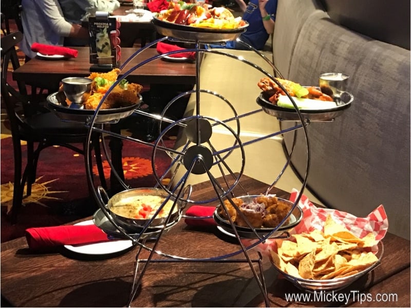 A Ferris wheel appetizer server spins at Planet Hollywood Observatory, with Disney World guests dining in the lively background.