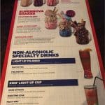 Planet Hollywood Disney Springs menu with over-the-top milkshakes, fun drinks, and glowing souvenir cups on a wooden table.
