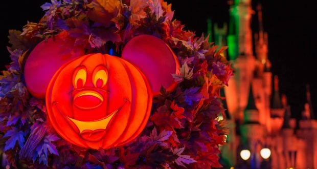 Mickey Mouse pumpkin glows amid autumn leaves as Cinderella Castle shines, capturing the Halloween magic of Disney World’s party.